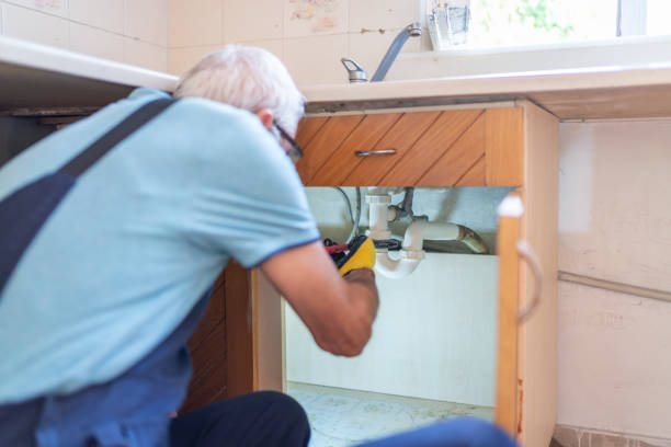 Senior Plumber Fixing The Pipes Under The Sink In The Kitchen